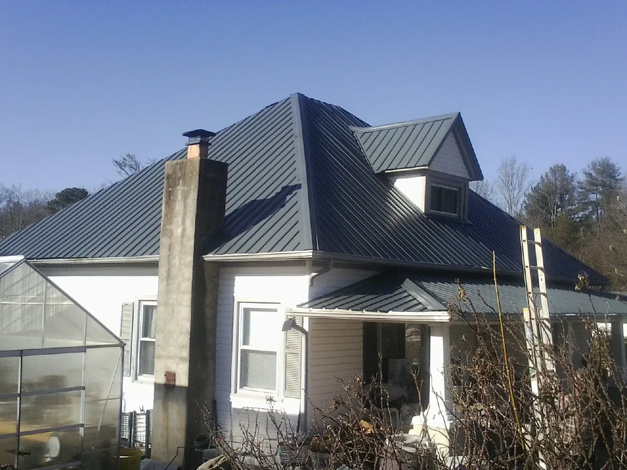 Dark blue standing seam metal roof on a white farmhouse with dormer — Slate & Tile Roof Repair by Roofing Brothers in Kent