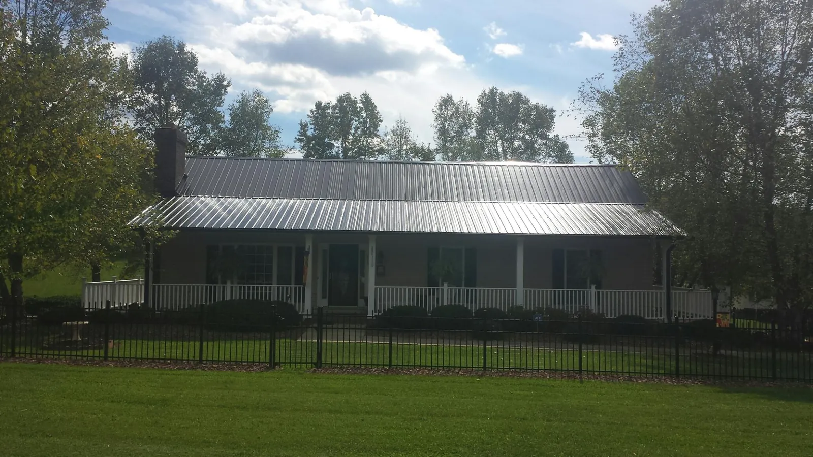 Gray metal roof on a brick ranch with a full width front porch — Gutter Guard Installation work by our crew in Kent